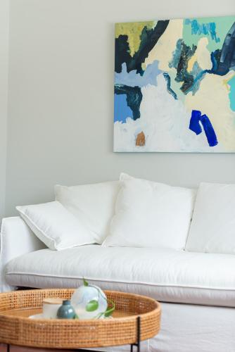 a living room with a white couch and a table at The Elements l Water l 4 Stunning Apartments each with Private Outdoor Dining l Walk to the Beach l Pet Family and Event Friendly l Wifi l Netflix l Outdoor Shower l Communal BBQ Pavilion and Lawn Area l in Christies Beach