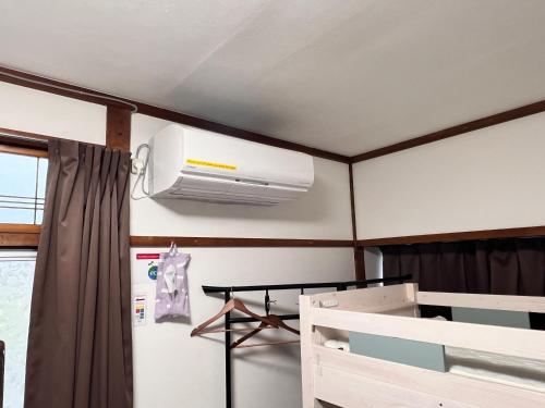 a ceiling fan in a room with a refrigerator at Hostel Murasaki in Takayama