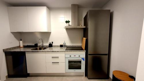 a kitchen with white cabinets and a black refrigerator at BlueSkyEsteponaGardens in Estepona
