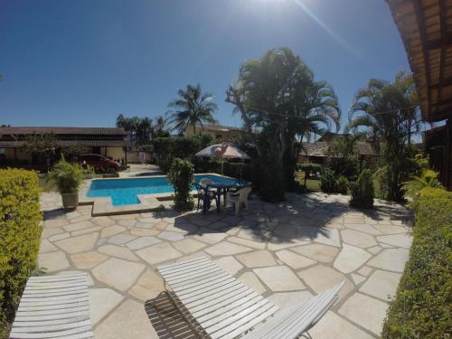 a patio with a table and chairs next to a pool at pousada dos sonhos in Pirenópolis