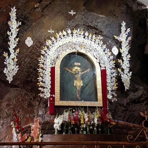 a shrine with a painting of a cross and flowers at La Casa Blanca 