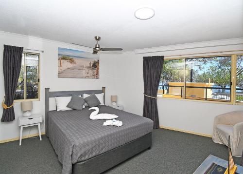 een slaapkamer met een bed met twee zwanen erop bij Alexander Beachfront Apartments in Hervey Bay