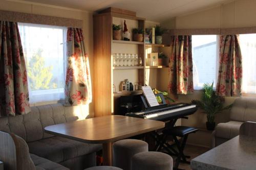 sala de estar con piano y mesa en Cosy beachfront getaway in Mersea en West Mersea
