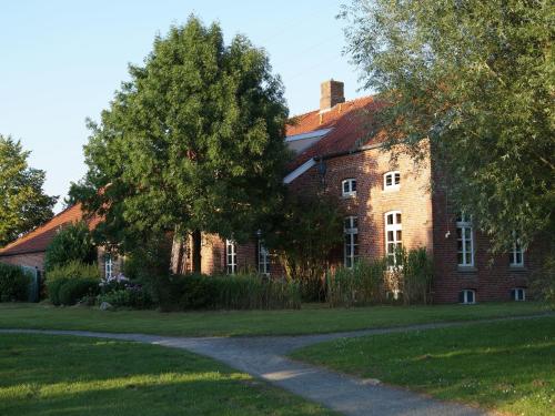 a large brick building with a tree in front of it at Gasthuus Ulenhoff in Westoverledingen