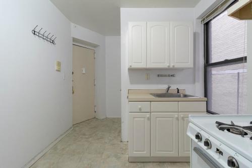 uma cozinha com armários brancos e um lavatório em The Upper East Side Monthly Rentals Apartments em Nova York