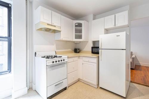 Biała kuchnia z kuchenką i lodówką w obiekcie The Upper East Side Monthly Rentals Apartments w Nowym Jorku