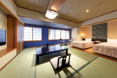 Un dormitorio con 2 camas y un escritorio en una habitación. en Suhaku, en Suwa