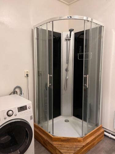 uma cabina de duche em vidro numa casa de banho ao lado de uma máquina de lavar roupa em Lägenhet med sjötomt. Vildmark i tätort. em Umeå