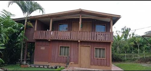 ein Holzhaus mit einem Balkon und einer Palme in der Unterkunft Cabaña Familiar 7 Colinas in San Vito