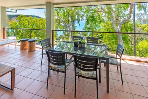 a dining room with a glass table and chairs at Compass Point on Hamilton Island by HIHA in Hamilton Island