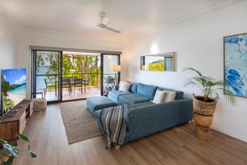 a living room with a blue couch and a table at Compass Point on Hamilton Island by HIHA in Hamilton Island