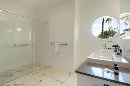 a white bathroom with a sink and a mirror at Compass Point on Hamilton Island by HIHA in Hamilton Island