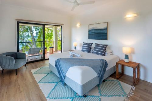 a bedroom with a bed and a chair and a window at Compass Point on Hamilton Island by HIHA in Hamilton Island
