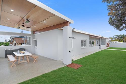 a backyard with a table and a white house at The Elements l Water l 4 Stunning Apartments each with Private Outdoor Dining l Walk to the Beach l Pet Family and Event Friendly l Wifi l Netflix l Outdoor Shower l Communal BBQ Pavilion and Lawn Area l in Christies Beach
