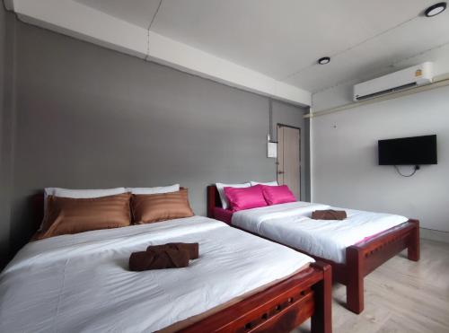 two beds in a room with a tv on the wall at Zamanja Betong106 Main Street in Yala