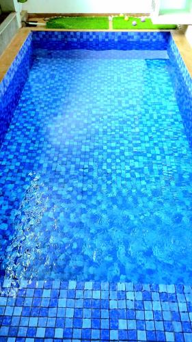 a swimming pool with blue tiles in the water at MG'S Villa in Batu