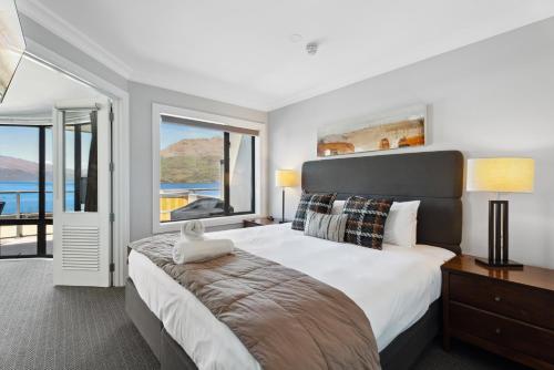 Un dormitorio con una cama grande con una ventana grande. en 2-bedroom Penthouse Apartment with Spa - The Beacon 1004, en Queenstown