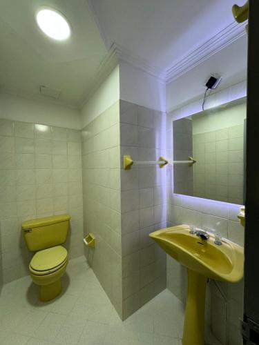 uma casa de banho com um WC amarelo e um lavatório. em Rustik House em Medellín