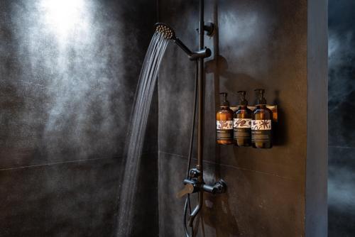 a shower in a bathroom with bottles of alcohol at Toteme Glamping and Hot Spring Kintamani in Kubupenlokan