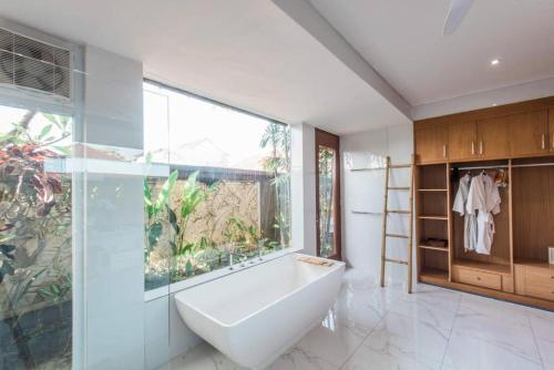 een badkamer met een bad en een groot raam bij Villa Lacasa2- modern tropical 2BR Villa with butler in Legian