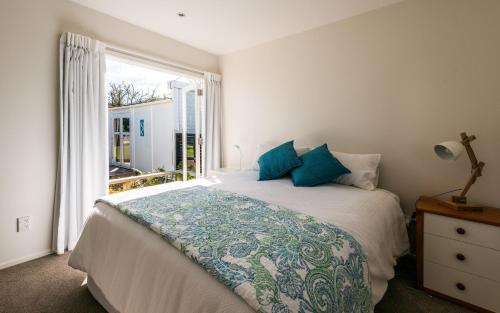 a bedroom with a bed with blue pillows and a window at Island Time in Oneroa