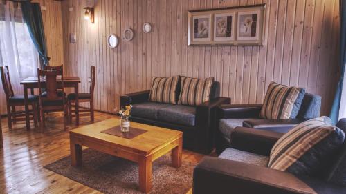Sala de estar con 2 sofás y mesa de centro en Cabaña Los Coihues, en Puerto Montt