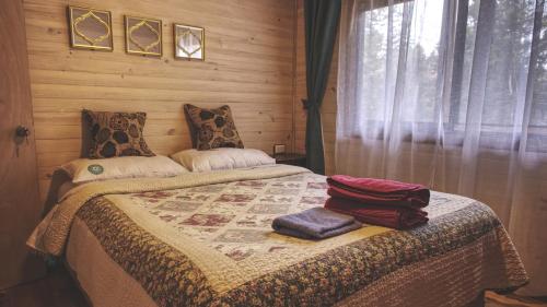 a bedroom with a bed with two towels on it at Cabaña Los Coihues in Puerto Montt