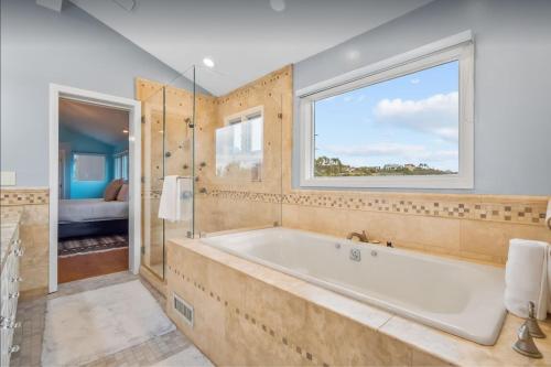 un bagno con ampia vasca e finestra di La Jolla Luxury Estate - Massive Yard, Pool-Spa, Fast WiFi & Outdoor Fireplace a San Diego