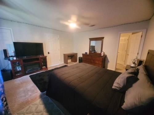 a bedroom with a large bed and a flat screen tv at Beautiful 3 bedroom home 4 minutes from the beach in Pensacola