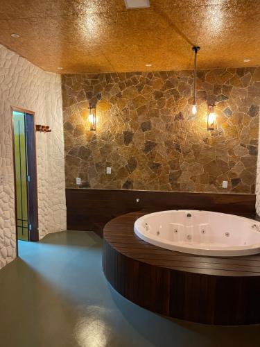 a bathroom with a large tub with a stone wall at Kanto do Chico in Icaraí