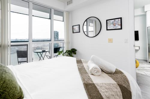 a white bedroom with a large bed and a mirror at Stylish Suite at 300 Front Street W in Toronto