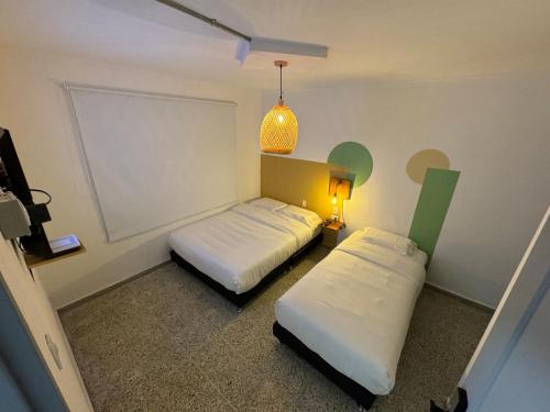メデジンにあるRustik Houseのベッド2台、照明、ランプが備わる客室です。