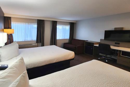 a hotel room with two beds and a desk at Days Inn by Wyndham Kelowna in Kelowna