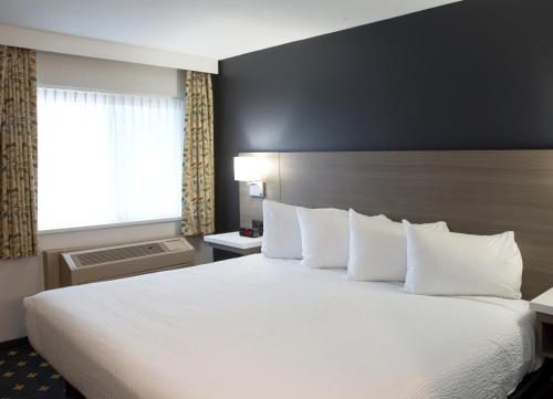a hotel room with a large bed with white pillows at Days Inn by Wyndham Kelowna in Kelowna