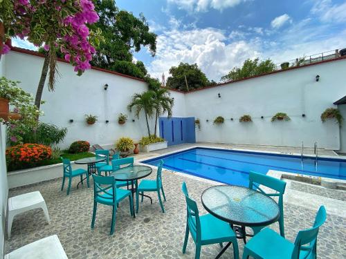 a patio with tables and chairs next to a swimming pool at Hotel San Julian in Buga