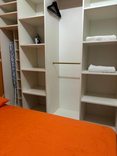 um armário com prateleiras brancas e uma cama laranja em Appartement or em Caiena