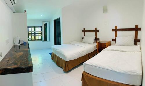 2 Betten in einem Zimmer mit weißen Wänden in der Unterkunft Fikri Wetland Guesthouse & Resort 