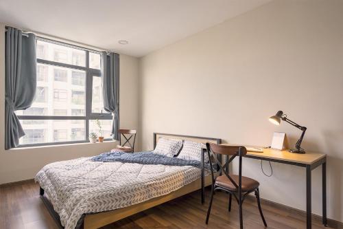 Un dormitorio con una cama y un escritorio y una ventana. en Roomio De Capella - Share Apartment, en Ho Chi Minh