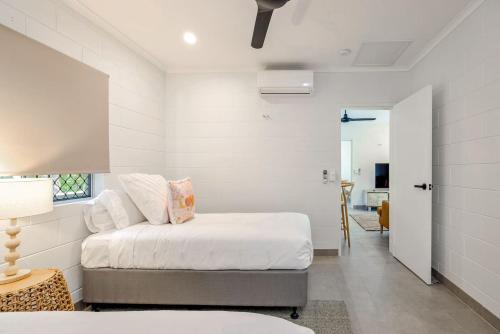 a white bedroom with a bed and a table at The Tropical Trinity - A Breezy Beachside Getaway in Trinity Beach