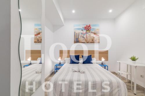 a white bedroom with two beds with blue pillows at LooP Las Ventas in Madrid