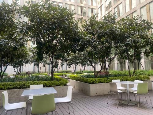 eine Terrasse mit Tischen, Stühlen und Bäumen sowie ein Gebäude in der Unterkunft Acogedor y hermoso depto, en el C.Historico CDMX in Mexiko-Stadt