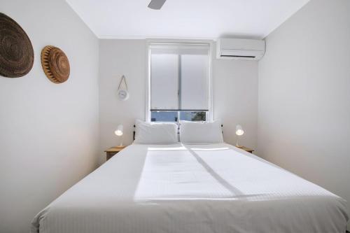 a white bedroom with a large bed and a window at The Hillside at Hamilton - A Fresh Riverfront Abode in Brisbane