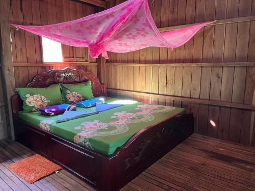 a bed in a wooden room with a pink mosquito net at Ratanakiri Farmhouse & Trekking in Banlung