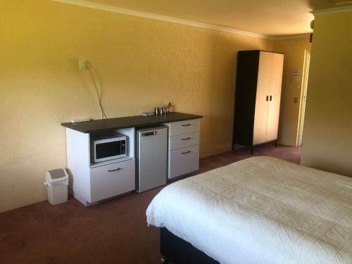 a hotel room with a bed and a microwave at Colonial Inn Guest Rooms in Yackandandah
