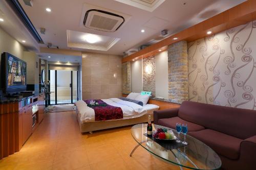 a living room with a bed and a couch at Hotel AXIS -アクシス- in Osaka
