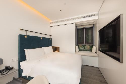 a bedroom with a white bed and a tv at Shanghai Autoongo Bund Hotel in Shanghai