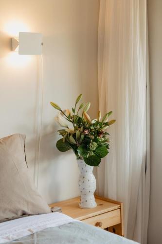 a vase of flowers on a table next to a bed at Buffalo Lodge in Coromandel Town