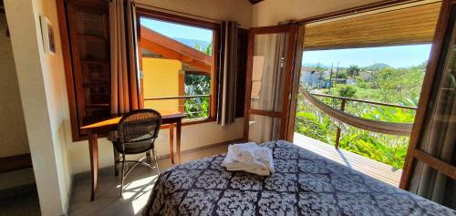 a bedroom with a bed and a desk and a window at Casa Bon Voyage - Guesthouse in Paraty