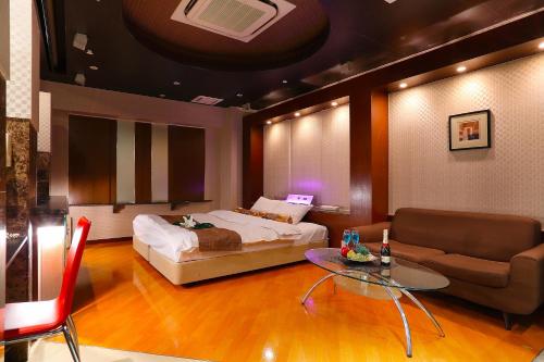 a bedroom with a bed and a table and a couch at Hotel AXIS -アクシス- in Osaka