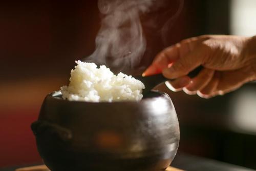 a person putting rice in a pot with smoke at 川魚・山菜料理　和田屋 in Hakusan